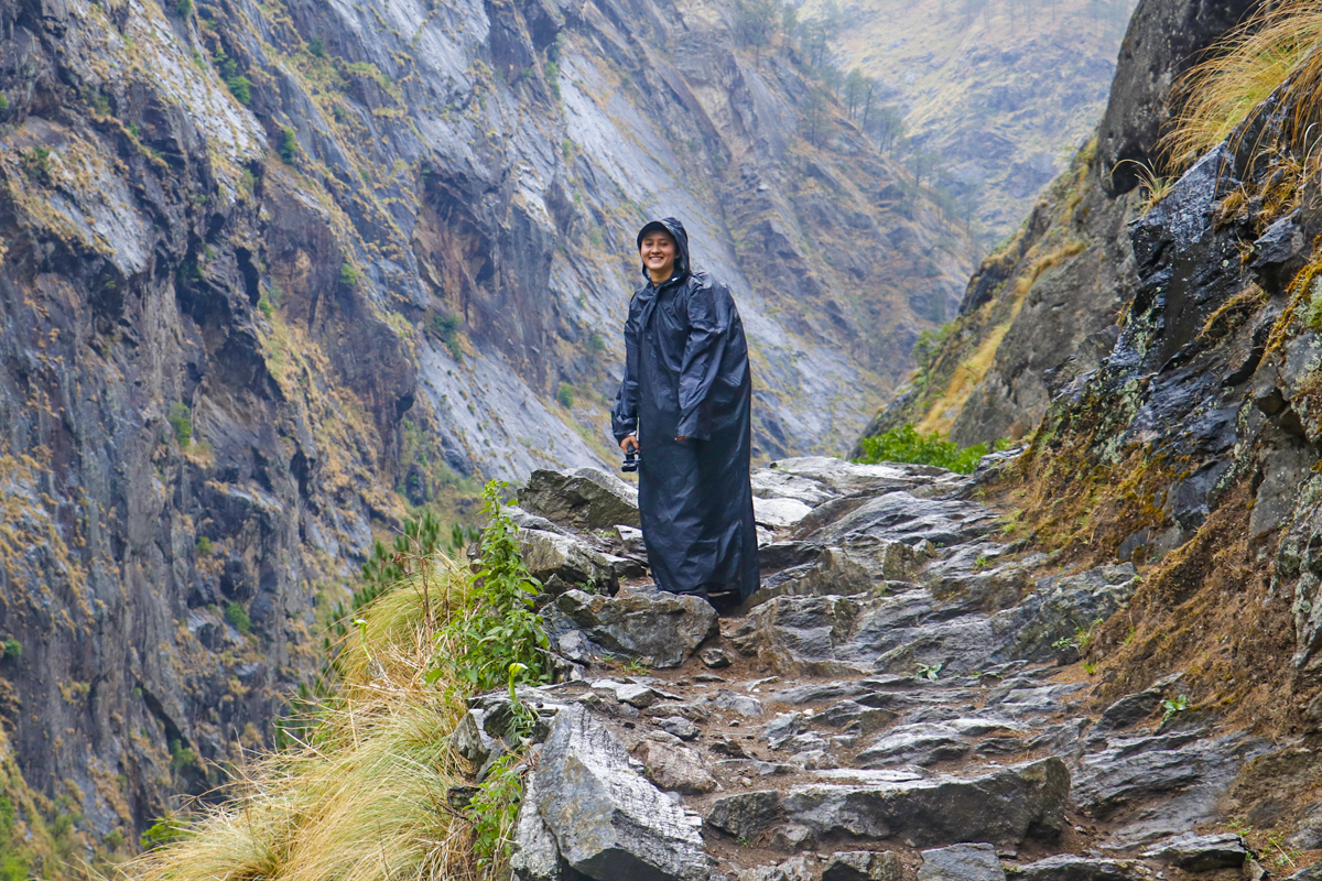 female trekker in black raincoat in monsoon trek